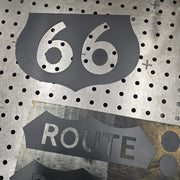 Black painted laser-cut steel Route 66 shield pieces on the BOCO Custom shop table, showing the 66 and ROUTE cutouts