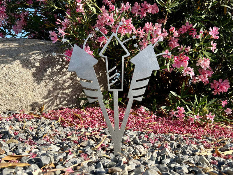 METAL FIREWORKS LAWN STAKE IN GARDEN, SHOWN IN RAW STEEL