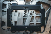 Artistic view of the raw steel Husky Build-Out locking mounting plate alongside shop fabrication materials, highlighting the American-made industrial quality of BOCO Custom mounts.
