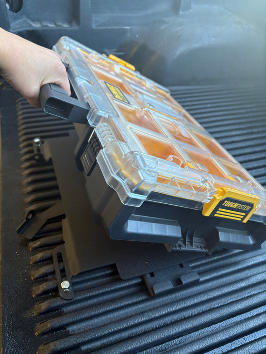 Image showing a DeWalt toolbox being placed into the custom mounting plate, which is installed in the bed of a truck, capturing the alignment process.