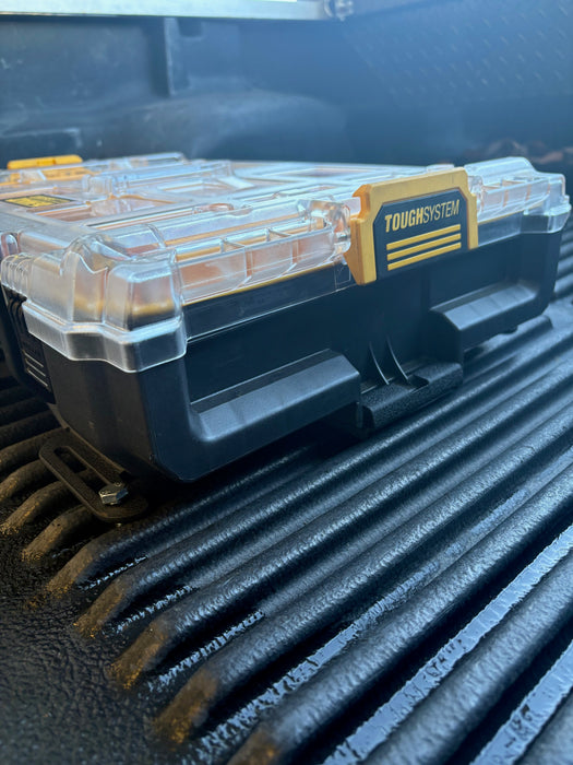 Close-up image of the DeWalt toolbox securely fastened in the custom mounting plate, focusing on the mounting mechanism, with the truck bed visible in the background.