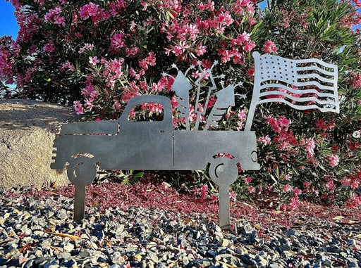 Decorative metal sculpture of a truck, horse, and flag in front of pink flowers