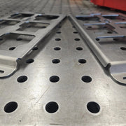 Bent edge and unbent edge of two B-Grade Packout mounting plates side by side